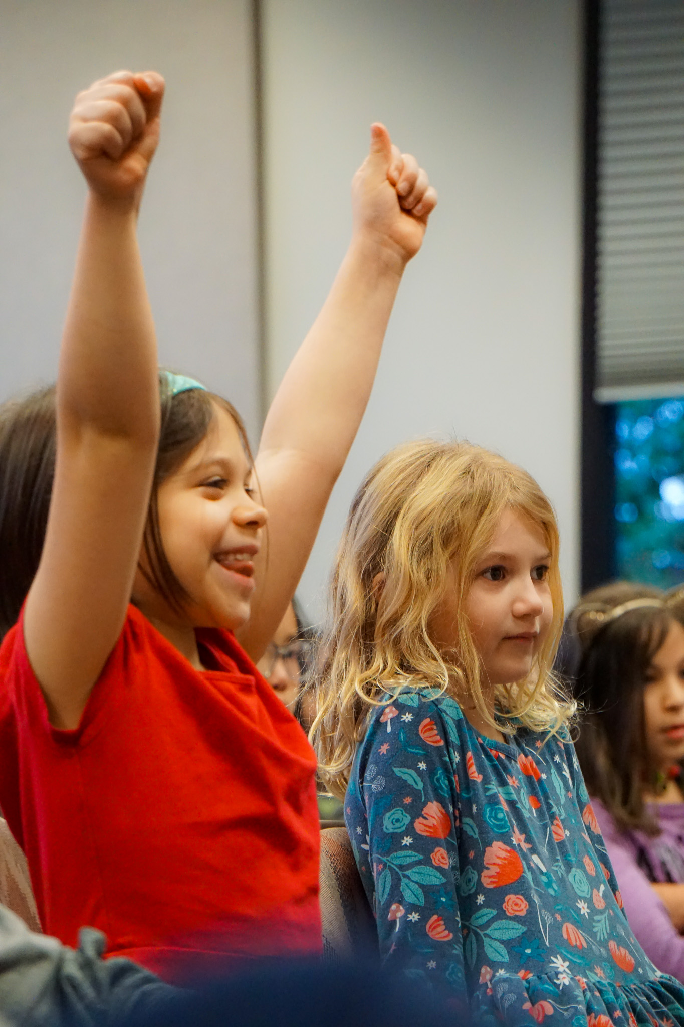 Elementary students raising her hands while cheering for another student