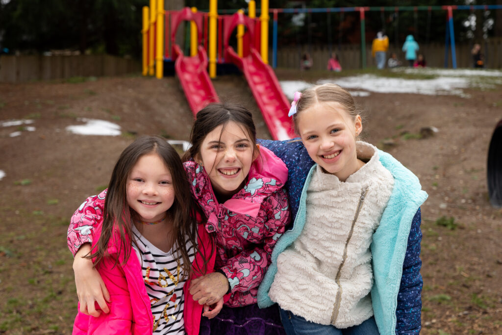 Elementary students posing together on playground in front of slide